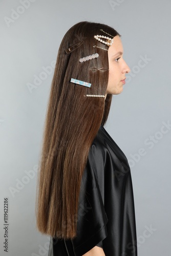 Teenage girl with stylish hair clips on light grey background photo