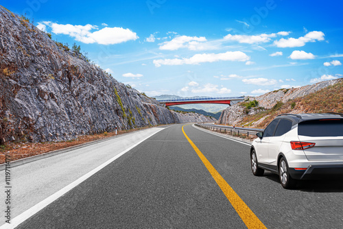 Obraz na płótnie White car driving on highway with mountains in background. Car travel - concept. w salonie