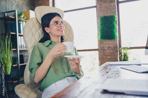 Young businesswoman in office enjoying a coffee break while wearing elegant formalwear photo