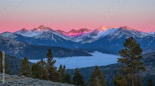 Majestic mountain range at dawn, snow-capped peaks bathed in vibrant pink and purple hues, tranquil valley filled with fog, evergreen trees, and a meadow below.