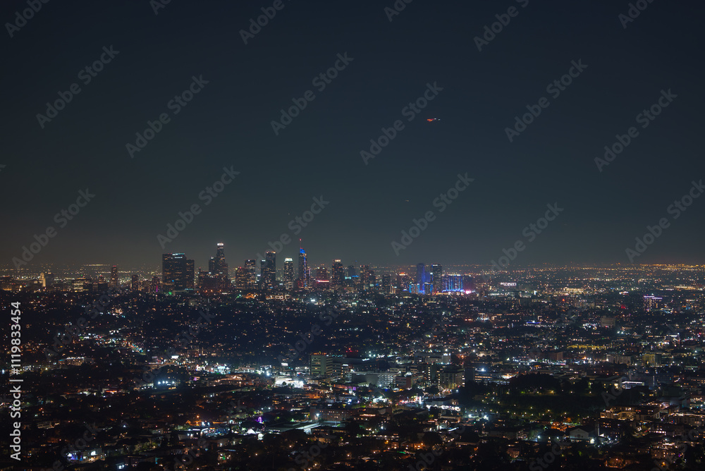 The Los Angeles skyline is illuminated at night, featuring the U.S. Bank Tower. City lights spread across the urban landscape, highlighting downtown. The Los Angeles skyline is illuminated at night, featuring the U.S. Bank Tower. City lights spread across the urban landscape, highlighting downtown.