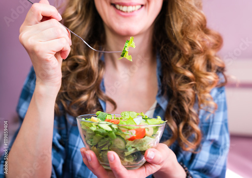 Young woman eating diet vegetable salad and smiling. Close-up. Selective focus.