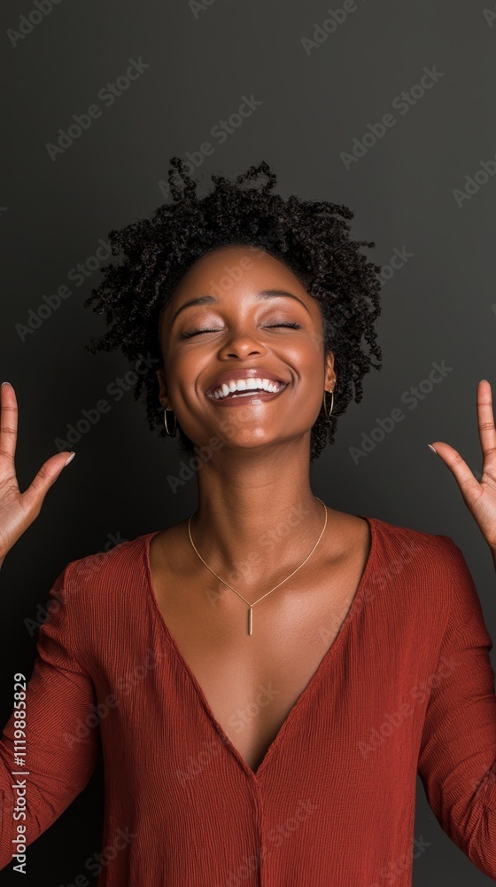 Brightly smiling woman shows victory sign in studio portrait against dark background Brightly smiling woman shows victory sign in studio portrait against dark background