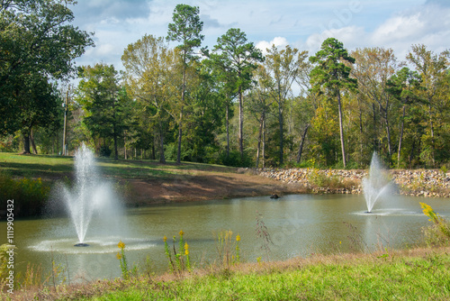 View of the Linden City Park with small pond and fountains in fall, Cass County, Texas, USA