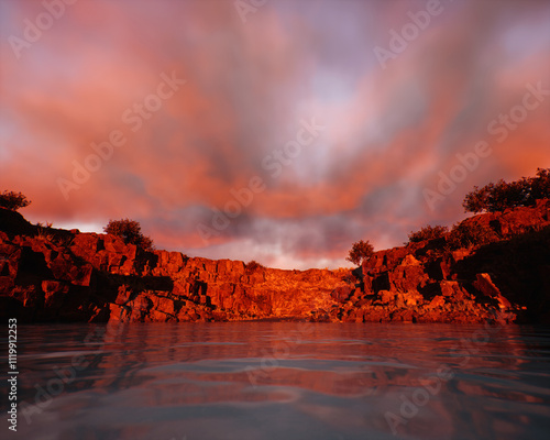 Obraz na płótnie Quarry slate with water and some trees under a sunset cloudy sky. 3D render. w salonie