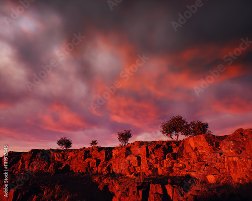 Obraz na płótnie Quarry slate with some trees under a sunset cloudy sky. 3D render. w salonie