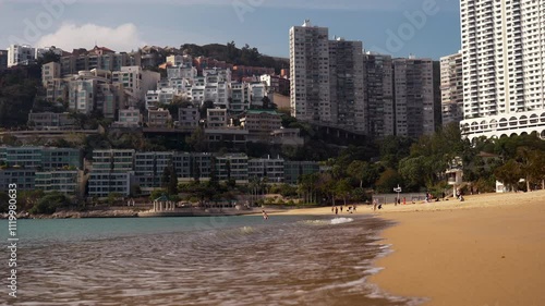 Beautiful sandy beach by the sea and the big city of Hong Kong in the background in sunshine