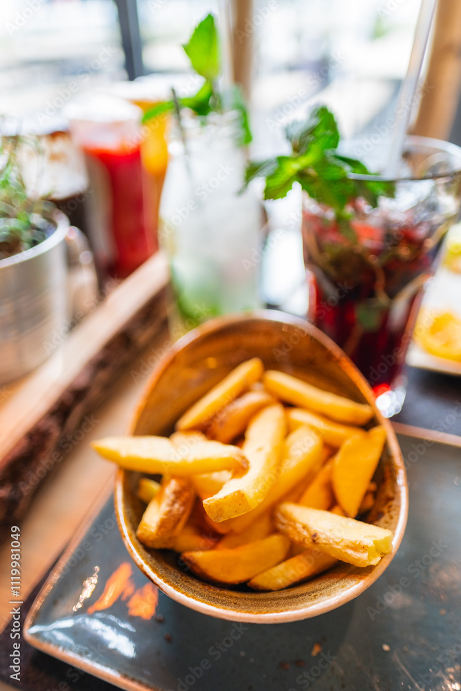 Close-Up of a Bowl of Freshly Cooked French Fries with Refreshing Summer Drinks in the Background, Creating a Vibrant and Relaxing Dining Atmosphere at a Modern Cafe or Restaurant Setting Close-Up of a Bowl of Freshly Cooked French Fries with Refreshing Summer Drinks in the Background, Creating a Vibrant and Relaxing Dining Atmosphere at a Modern Cafe or Restaurant Setting