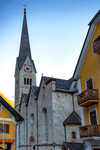 Postcard vertical view of the roofs of houses and the church spire in the village of Hallstatt in winter, when the mountain slopes are covered with snow. Travel in Hallstatt, Austria 