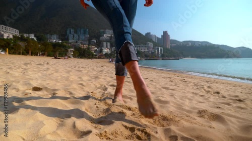 Legs of a beautiful young woman walking in slow motion along the Hong Kong beach in daytime