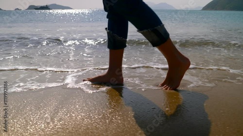 Legs of a beautiful young sporty woman walking in slow motion along the Hong Kong beach in sunshine