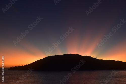 Stunning Pacific Ocean sunset with beams of colourful light shining up from the sea and islands in Fiji photo