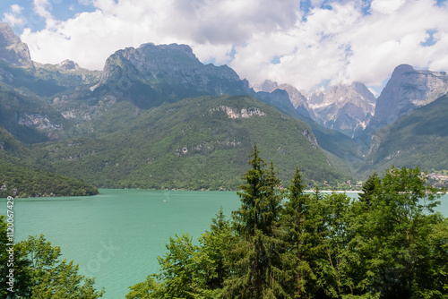 Greenery frames alpine retreat village at idyllic mountain lake Lago di Molveno with scenic view of majestic mountains Brenta Dolomites, National Park Adamello Brenta, Trentino, Italy. Summer lakeside photo