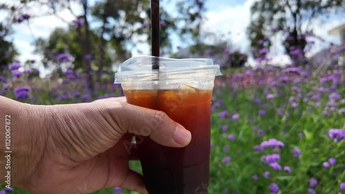 Man drinking coffee at verbena flower field.