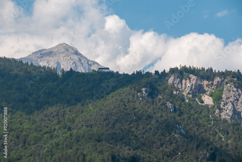 Scenic view of Cable car Funivie Molveno Pradel alpine retreat town Molveno, Trentino, Italy. Surrounded by forest and mountains of Brenta Dolomites. Tourism in Italian Alps. Cottage on top of hill photo