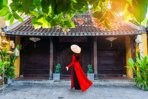 Young Vietnam woman wearing Ao Dai culture traditional walking on local street at Hoi an, Vietnam. photo