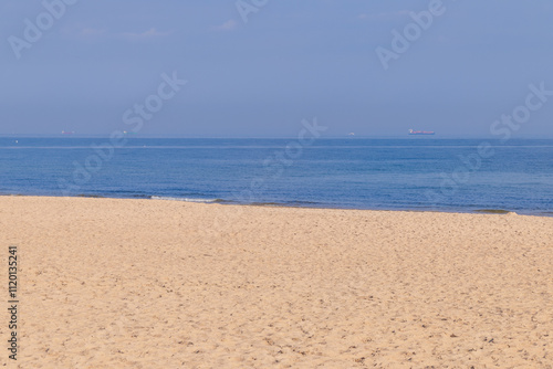 Sandy beach, blue sea and blue sky on a sunny day. Simple seascape.