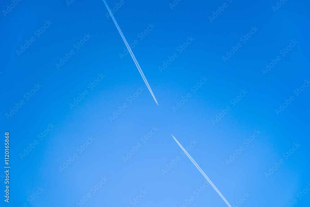 Contrail from airplanes in the blue sky. Two airplanes are flying towards each other. Contrail from airplanes in the blue sky. Two airplanes are flying towards each other.