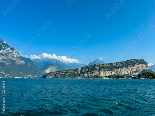 Ferry tour with scenic view of lakeside town Torbole and Riva at Garda Lake, Trentino, North Italy. Surrounded by unique rugged rock formation Monte Brione, Garda Hills. Summer lakeside vacation photo