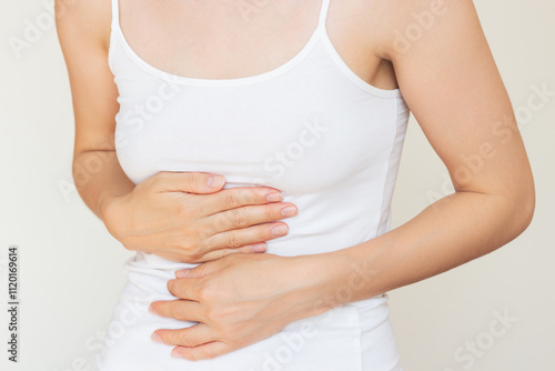 Wallpaper Mural A young woman in white clothes holding her stomach with both hands, experiencing severe acute stomach pain, suffering from pancreatitis, heartburn, gastritis. Medicine and healthcare. Torontodigital.ca