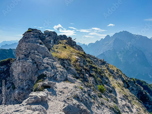 Hiking trail along remains of defensive line first world war on top of Jof di Miezegnot. Surrounded by majestic ridges of Julian Alps shrouded in misty haze, Friuli Venezia Giulia, Italy. Wanderlust photo