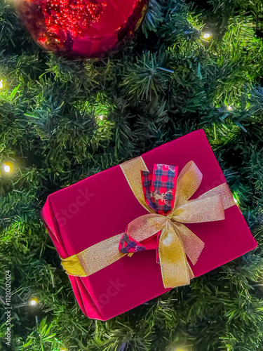 Elegant Red Christmas Gift with Golden Ribbon on Festive Tree