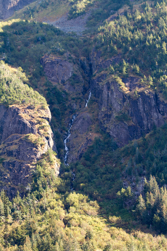 Scenic waterfall cascading down a lush, green mountain valley. Scenic waterfall cascading down a lush, green mountain valley.