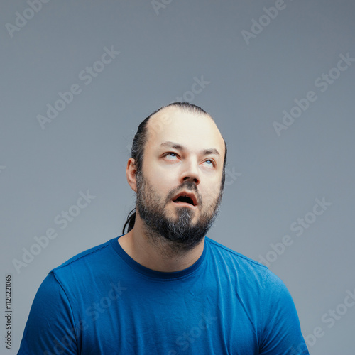 Frustrated man rolling his eyes on a grey background