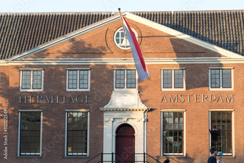 Front view of Hermitage Amsterdam with Dutch flag and evening light.
