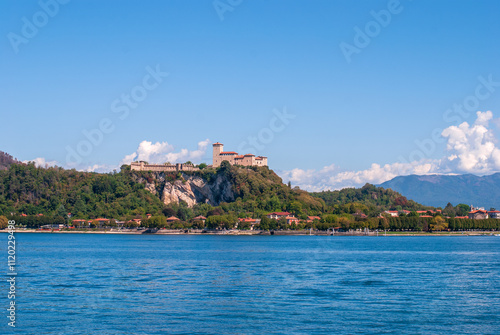 Vászonkép From Arona, the Rocca di Angera rises majestically above Lake Maggiore, its medieval fortress perched on a hill, offering a stunning contrast to the serene waters below