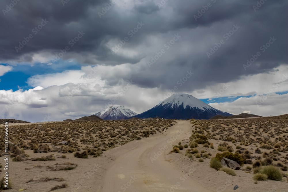 Parinacota volcano in Chile and Bolivia border. Volcanic cone summit beautiful landscape on stormy weather sky with dark clouds. Snowcapped volcano peak in the Andes. Chilean volcano top with snow Parinacota volcano in Chile and Bolivia border. Volcanic cone summit beautiful landscape on stormy weather sky with dark clouds. Snowcapped volcano peak in the Andes. Chilean volcano top with snow