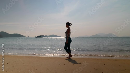 Beautiful mixed-race young woman walks in slow motion on the Hong Kong beach in sunshine
