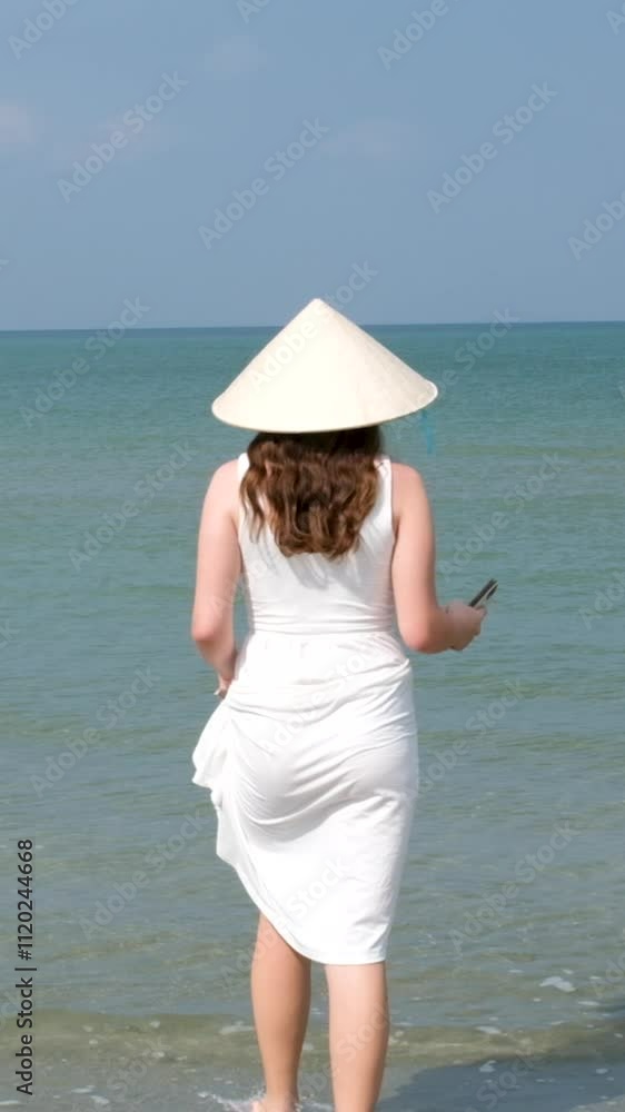 Woman in a white shirt walks along the beach of Persian Gulf in Dubai towards the sea against the backdrop of a beautiful sunset. Journey through the United Arab Emirates. Go Everywhere. Slow motion Woman in a white shirt walks along the beach of Persian Gulf in Dubai towards the sea against the backdrop of a beautiful sunset. Journey through the United Arab Emirates. Go Everywhere. Slow motion