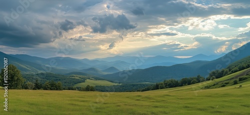 Panoramic mountain landscape with rolling hills and cloudy sky, lush green fields, distant mountains, and dramatic clouds, copy space for text