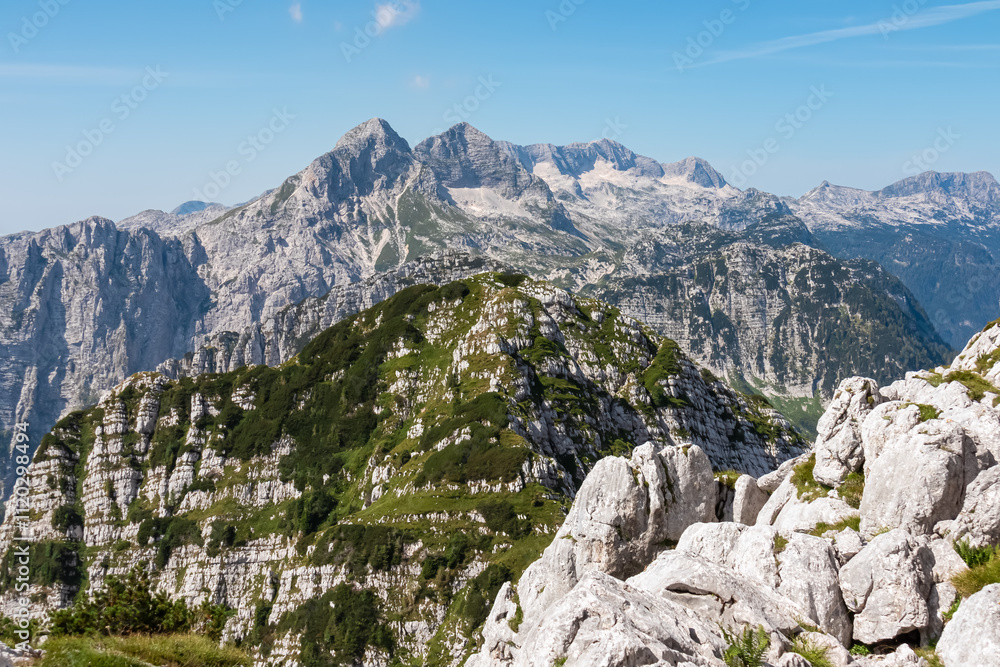 Scenic view of pristine rugged mountain peaks of Kanin massif, Julian Alps, Italy, Europe. Wild hiking trail along majestic ridges in Triglav National Park. Wanderlust alpine wilderness in summer. Awe Scenic view of pristine rugged mountain peaks of Kanin massif, Julian Alps, Italy, Europe. Wild hiking trail along majestic ridges in Triglav National Park. Wanderlust alpine wilderness in summer. Awe