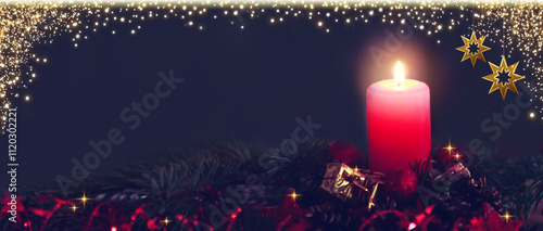 Red Advent candle with Christmas decoration isolated on black.