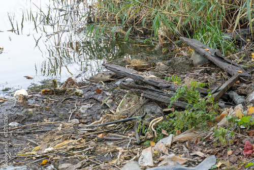 Garbage dump of rags rubber and cellophane in scattered in river. Plastic trash after picnic. People illegally throw rubbish. World ecology problem of environmental protection. Garbage in nature.