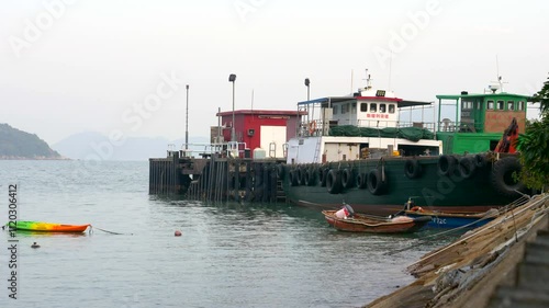 A small boat floats on the water against the backdrop of buildings in Hong Kong during the daytime