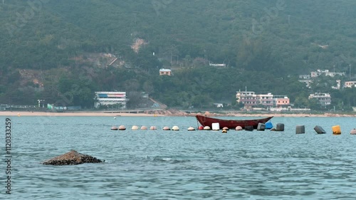 A boat floating in the water near the buoys at the Hong kong harbour in fog daytime