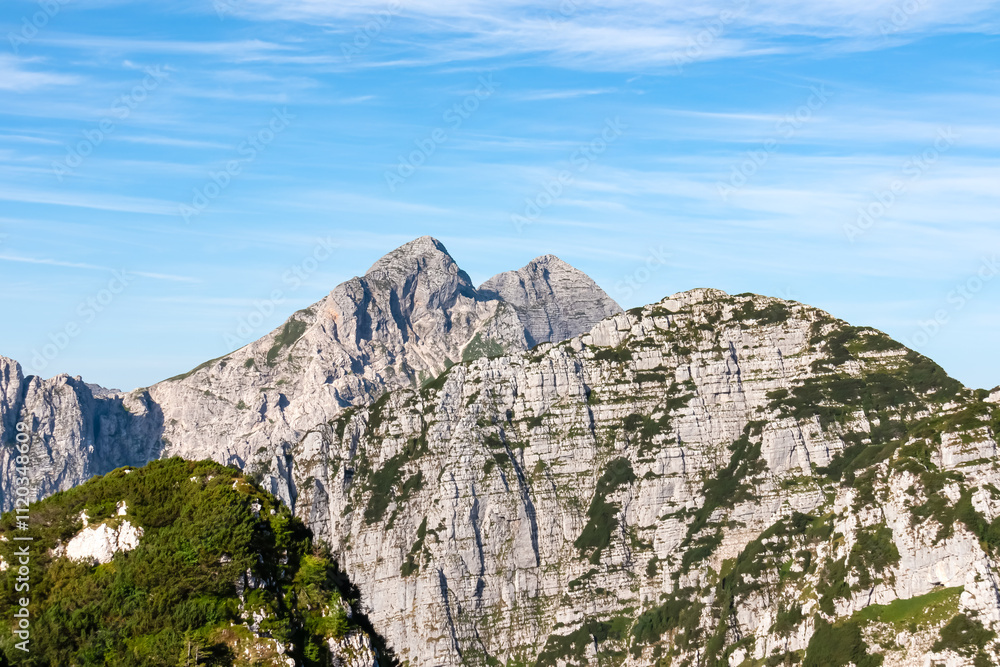 Scenic view of pristine rugged mountain peaks of Kanin massif, Julian Alps, Italy, Europe. Wild hiking trail along majestic ridges in Triglav National Park. Wanderlust alpine wilderness in summer. Awe Scenic view of pristine rugged mountain peaks of Kanin massif, Julian Alps, Italy, Europe. Wild hiking trail along majestic ridges in Triglav National Park. Wanderlust alpine wilderness in summer. Awe