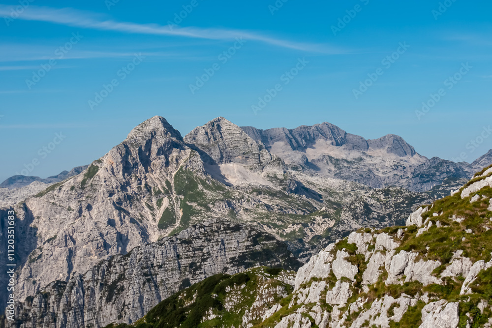 Scenic view of pristine rugged mountain peaks of Kanin massif, Julian Alps, Italy, Europe. Wild hiking trail along majestic ridges in Triglav National Park. Wanderlust alpine wilderness in summer. Awe Scenic view of pristine rugged mountain peaks of Kanin massif, Julian Alps, Italy, Europe. Wild hiking trail along majestic ridges in Triglav National Park. Wanderlust alpine wilderness in summer. Awe