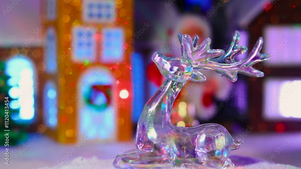 A deer figurine moves against the backdrop of a Christmas town with Santa Claus and a snowman A deer figurine moves against the backdrop of a Christmas town with Santa Claus and a snowman