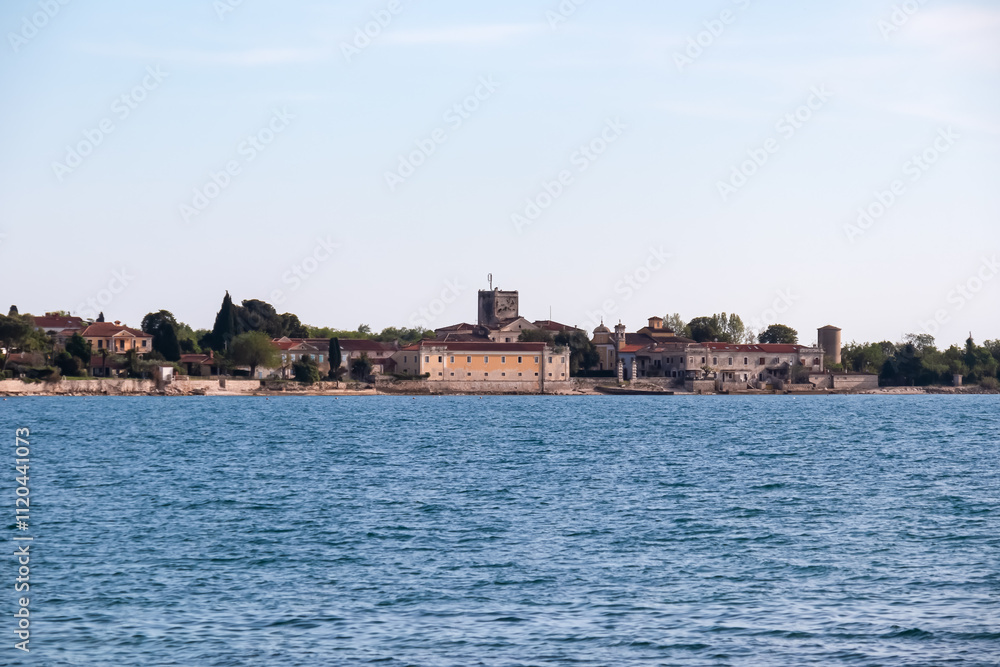 Fototapeta premium Scenic view of picturesque coastal town Dajla seen from shoreline of Karigador, Istria peninsula, Croatia, EU. Village is nestled along the waterfront of Adriatic Mediterranean sea. Summer vacation