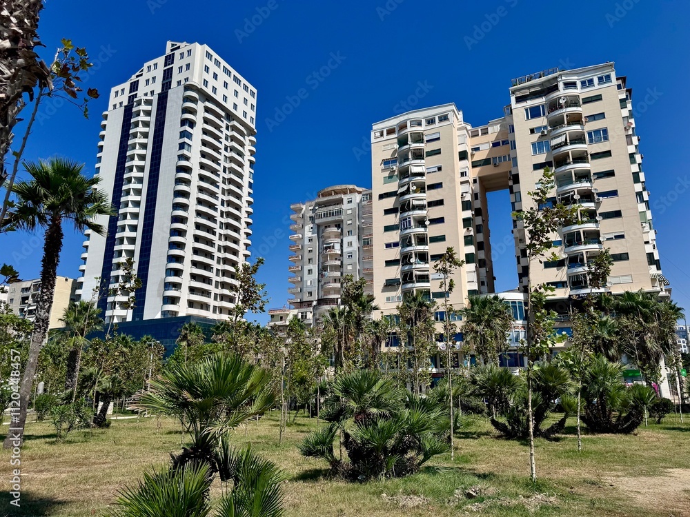 Fototapeta premium view of a park in Durres in Albania with palm trees and city buildings in the background on a sunny summer day 