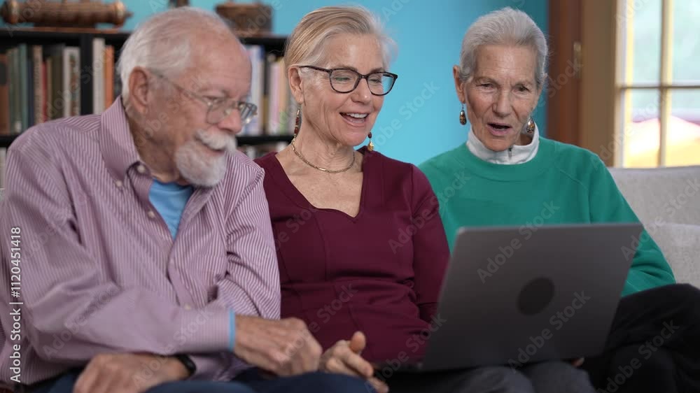 Three mature adults share laughter and smiles while engaging with family over a laptop, reflecting the joy of connection and togetherness in a cozy living space. Three mature adults share laughter and smiles while engaging with family over a laptop, reflecting the joy of connection and togetherness in a cozy living space.