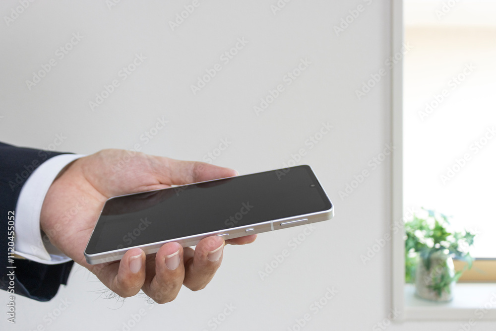 スーツを着てスマートフォンを持つ男の手(30代、日本人)