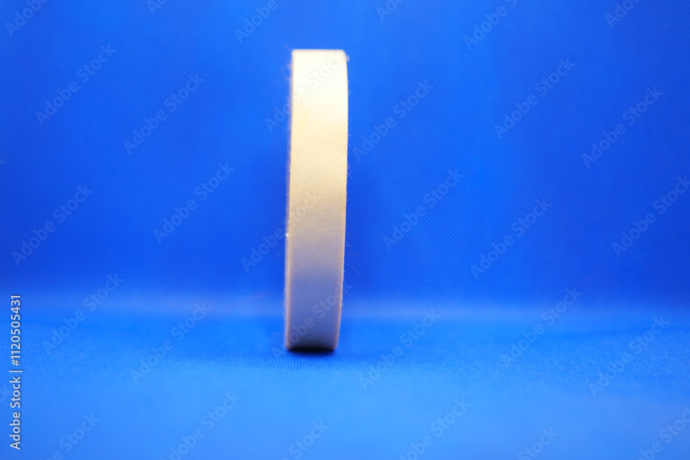 A roll of tape is currently positioned on a blue surface area A roll of tape is currently positioned on a blue surface area