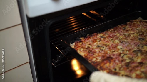 Woman's hands taking out homemade pizza from of oven