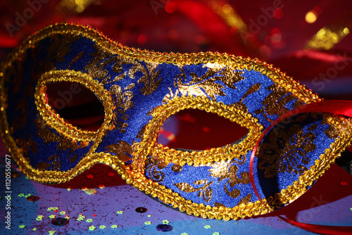 Beautiful carnival mask, ribbon and confetti on color background, closeup photo