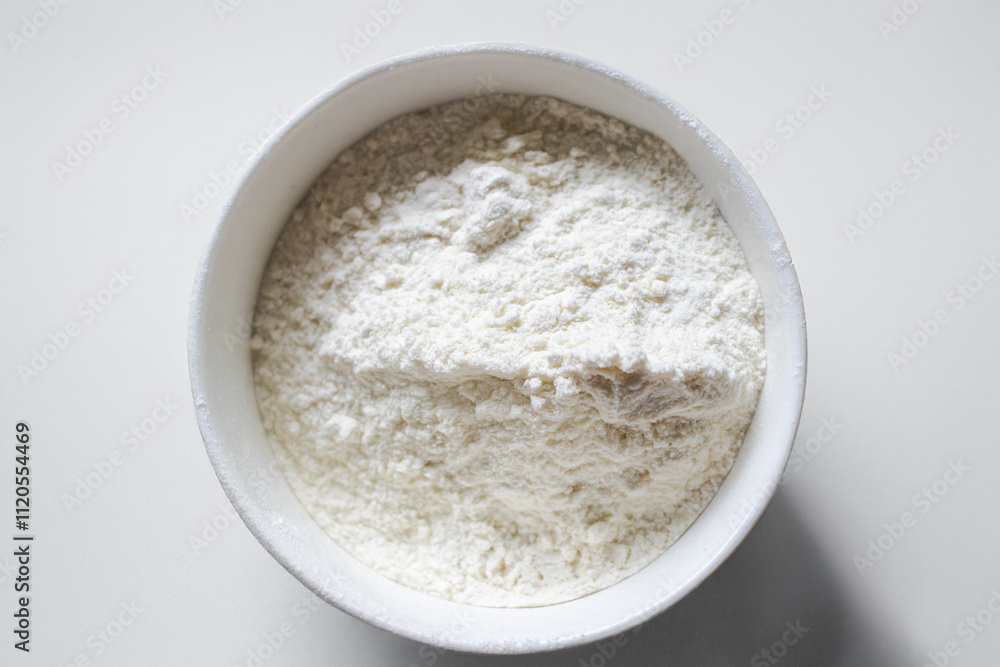 Close up of white flour, flour on a bowl on a white background, ingredient for food preparation. Isolated on a white background. Top view. White flour in a white bowl on a white background. Close up of white flour, flour on a bowl on a white background, ingredient for food preparation. Isolated on a white background. Top view. White flour in a white bowl on a white background.